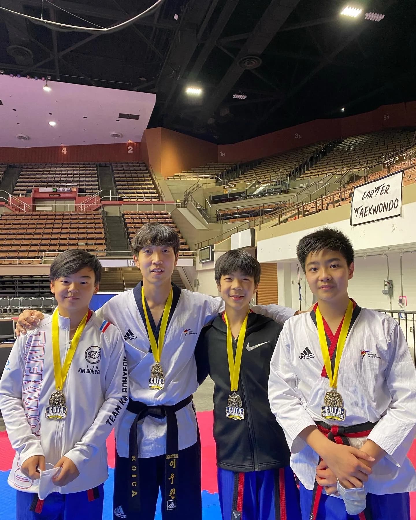 Master Lee with three of his students, all wearing medals, at a CUTA International tournament